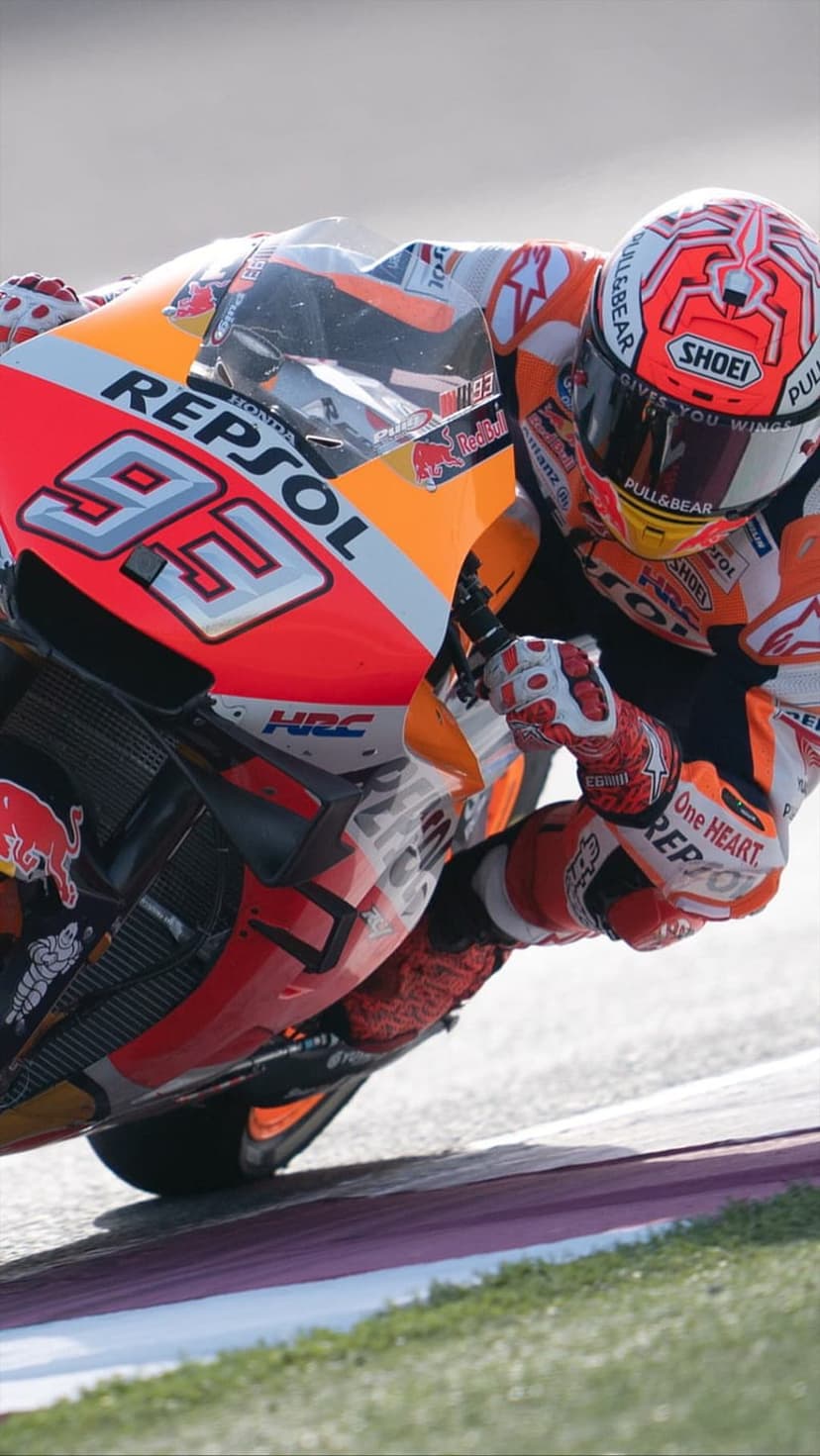 Marc Marquez #93 leans a Repsol Honda motorcycle deep into a turn on a paved race track with high-speed motion blur.