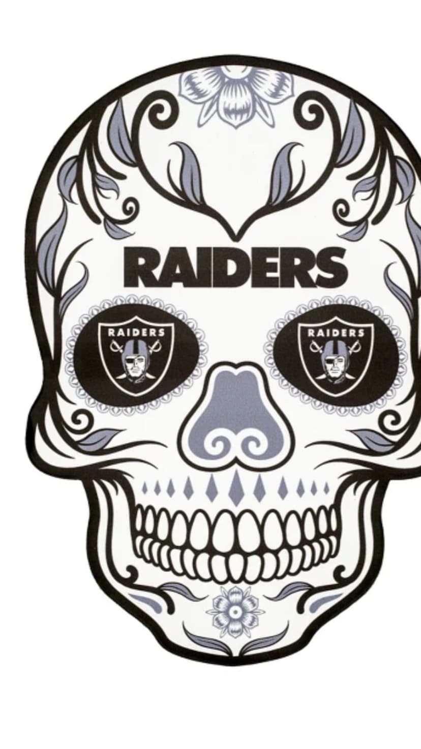 Sugar skull with Las Vegas Raiders shield logos in the eye sockets and floral vine patterns on a black background.
