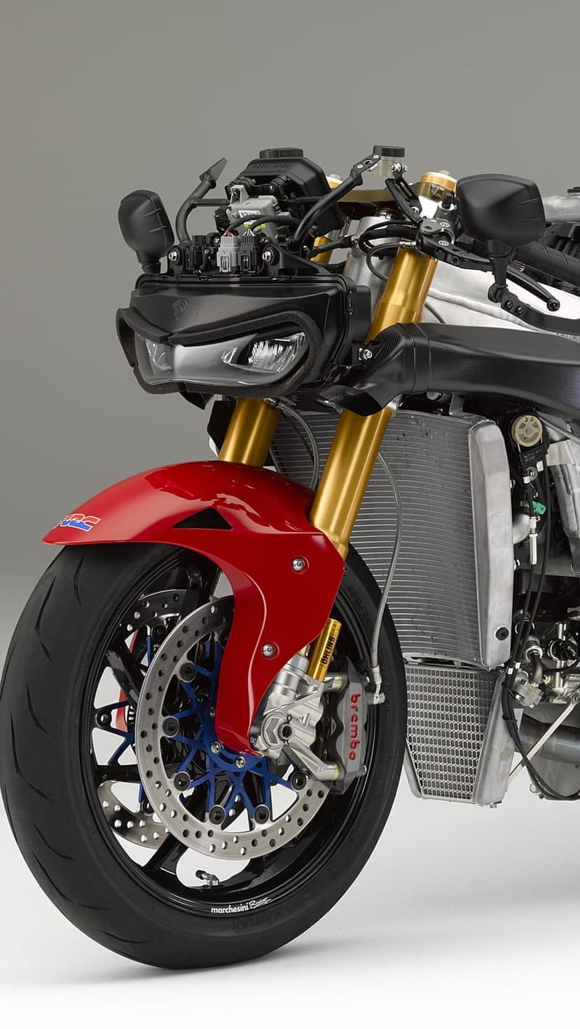 Red motorcycle fender and gold forks frame a Brembo brake system and blue wheel hub in a vertical macro shot.
