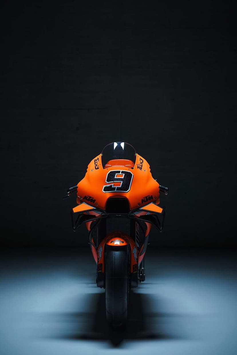 Orange KTM racing motorcycle with number 9 on the front fairing in a dark studio with dramatic lighting.