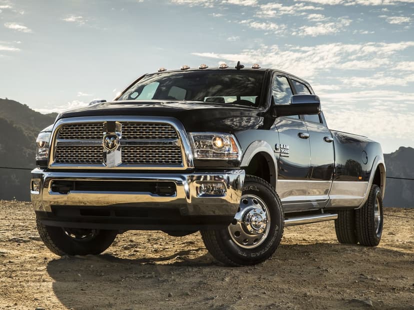 Black Ram 3500 dually pickup truck with chrome accents parked on a desert trail under a bright cloudy sky.