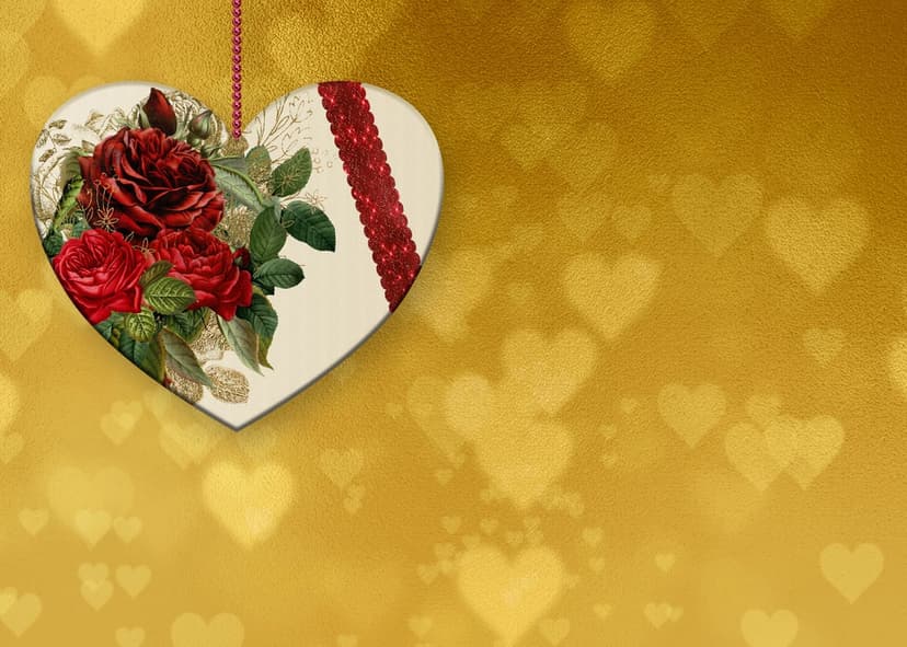 Red roses and green leaves fill a heart-shaped ornament hanging from a ribbon against a bokeh gold background.