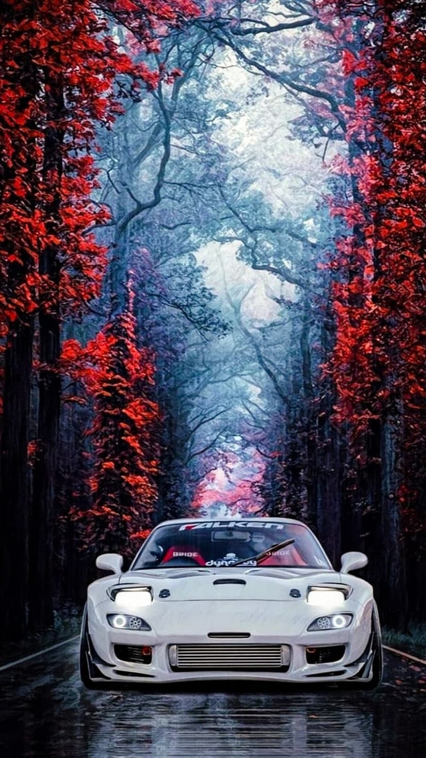 White Mazda RX-7 with glowing headlights on a forest road surrounded by red and blue foliage in thick mist.