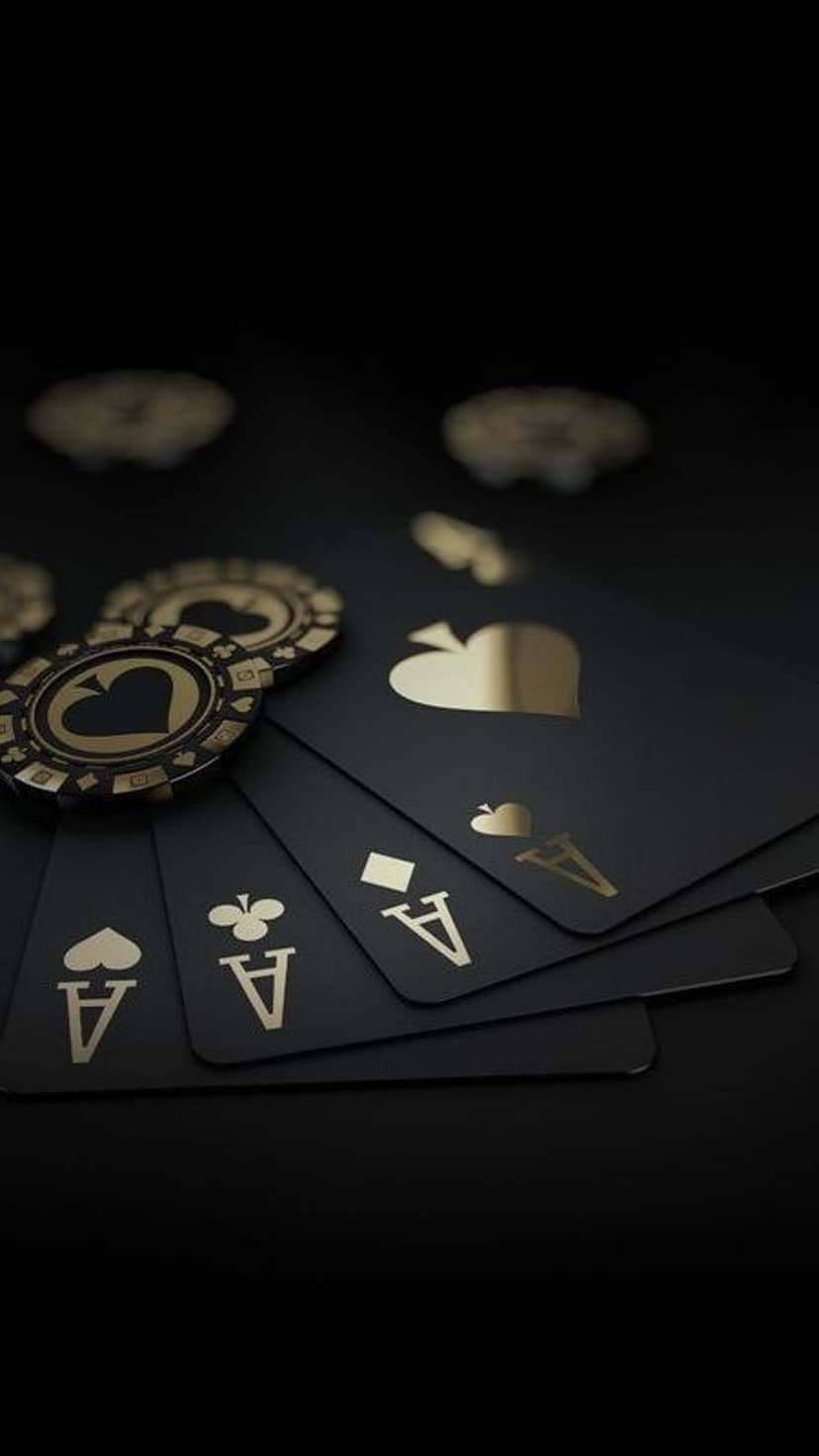 Four black ace playing cards with gold symbols underneath two metallic casino chips on a dark background.