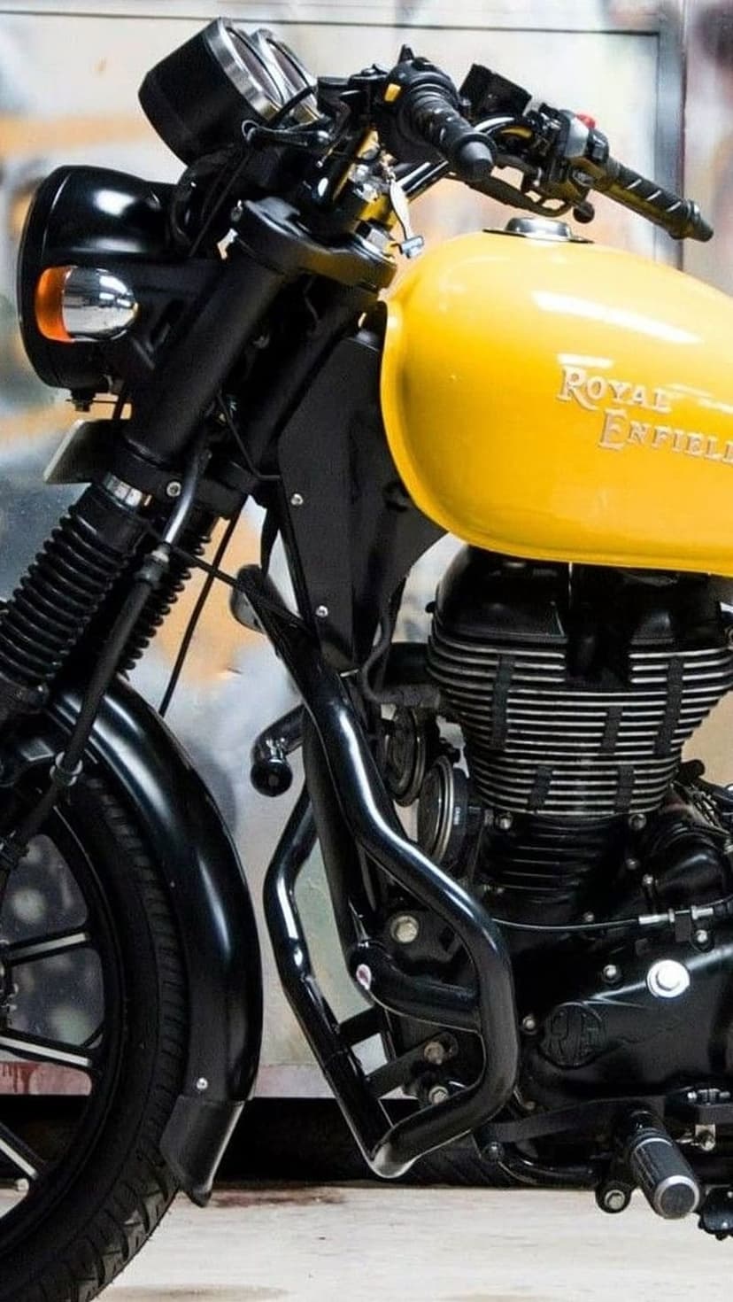 Yellow Royal Enfield fuel tank with embossed logo above a black air-cooled engine and chrome indicators.