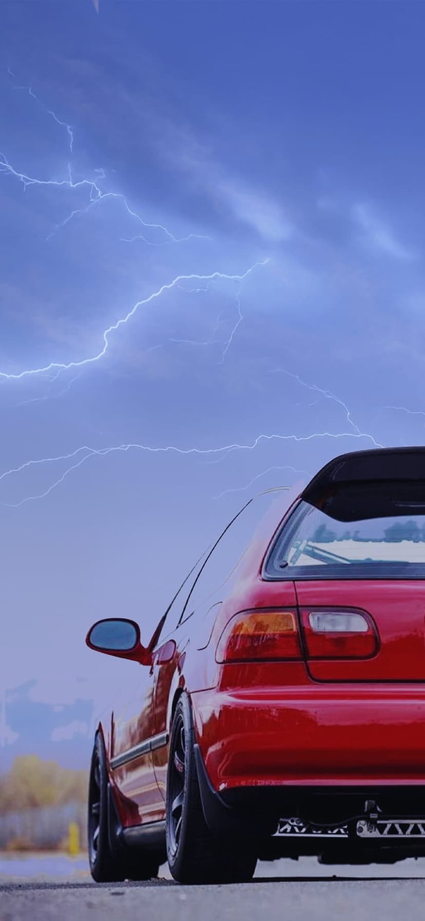 Red Honda Civic hatchback parked under a dark sky with branching blue lightning bolts hitting the horizon.