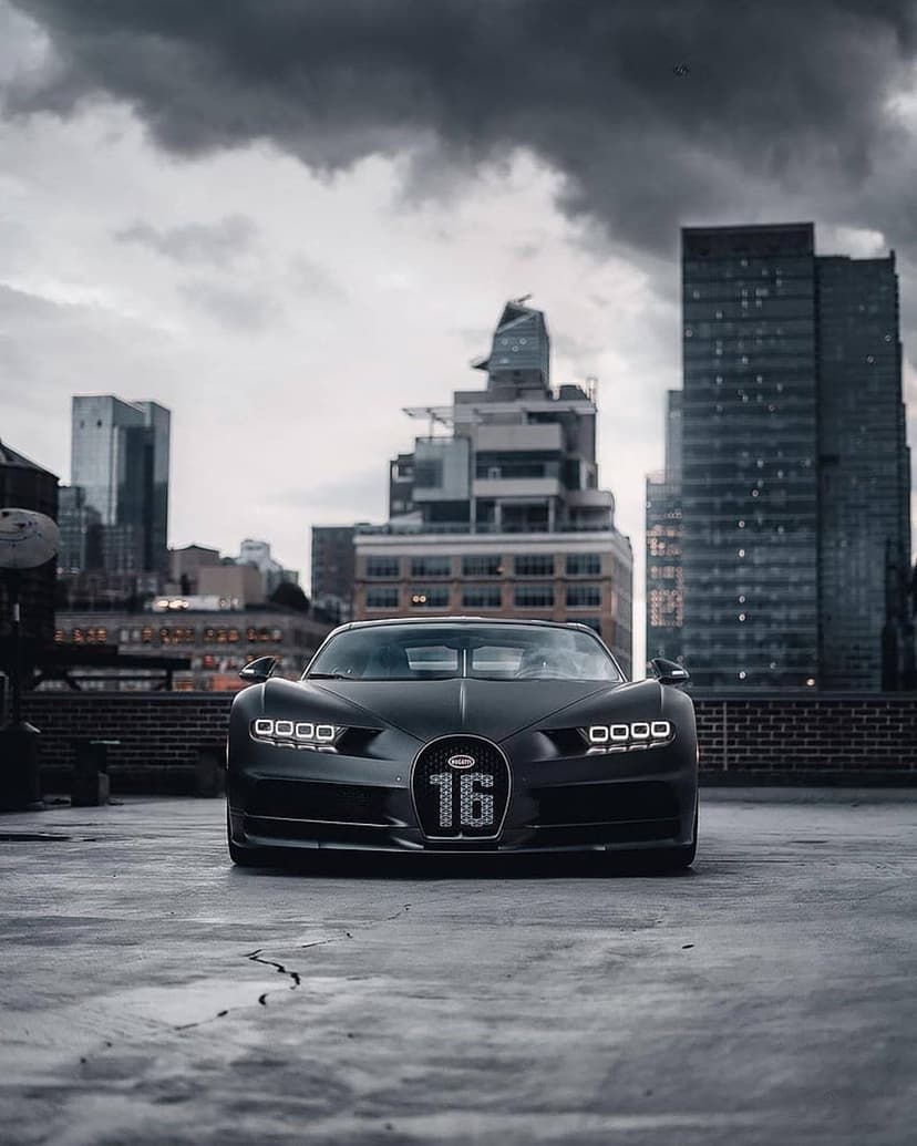 Bugatti Chiron Super Sport 300+ on a rooftop with skyscrapers and dark storm clouds in the urban background.