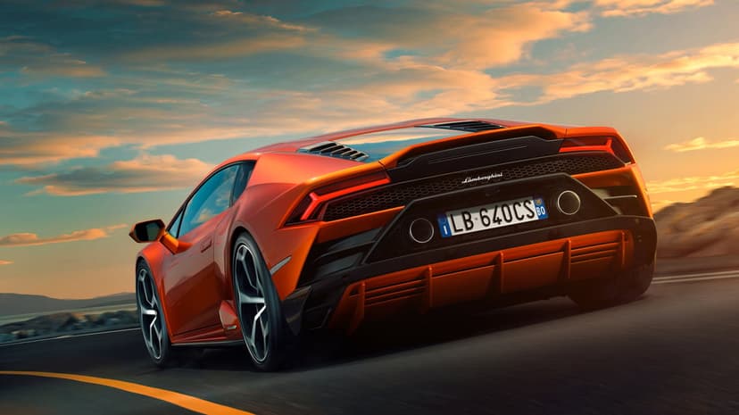 Orange Lamborghini Huracan Evo driving on a road at sunset with motion blur and a golden sky background.