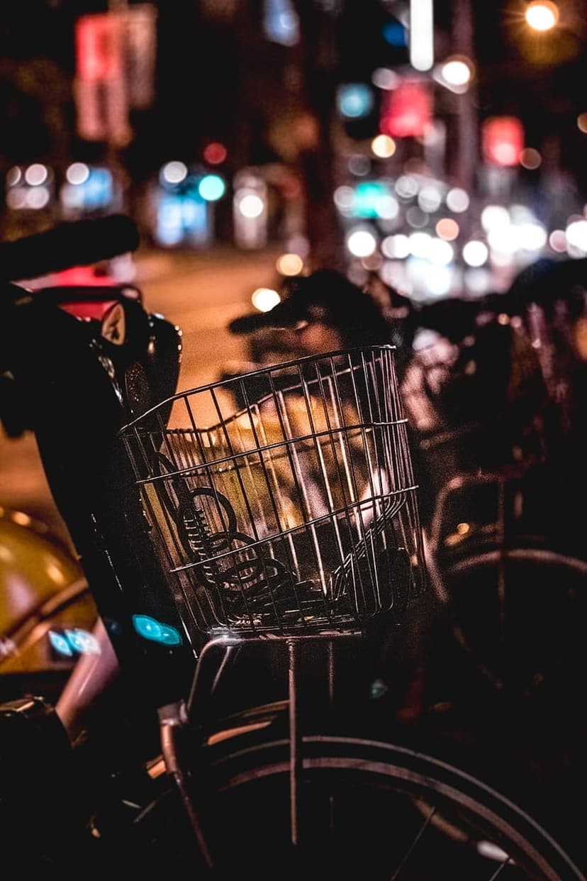 Metal bicycle basket close up against a background of glowing circular city light bokeh in the night street.