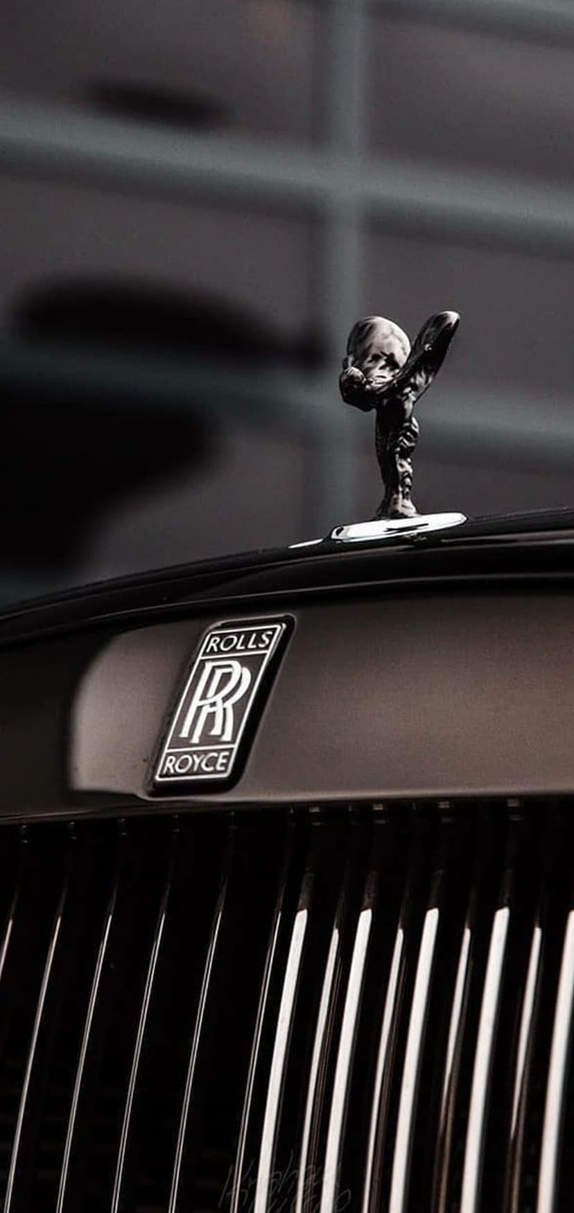Spirit of Ecstasy ornament and the interlocking RR emblem featured on a dark, polished luxury car hood.
