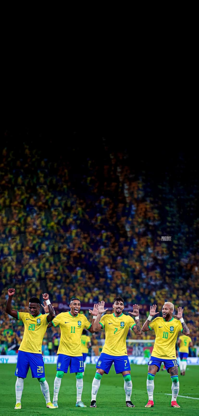 Brazilian football players in yellow jerseys cheering on a green field with a blurred crowd in the background.