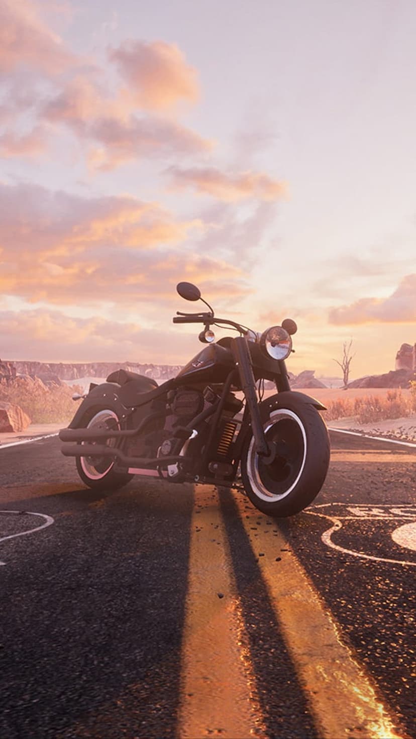 Black cruiser motorcycle parked on a desert highway with yellow lines under a pink and orange sunset sky.