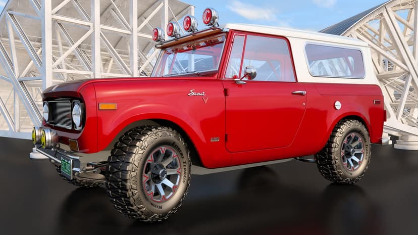 Red vintage International Harvester Scout with massive off-road tires and roof lights in a modern setting.
