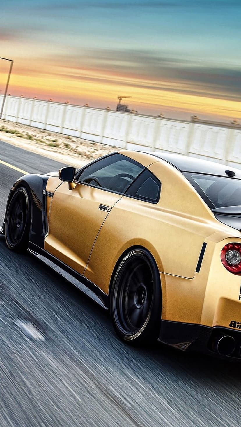 Golden Nissan GT-R with black trim speeding on a highway at sunset with motion blur on a vertical screen.