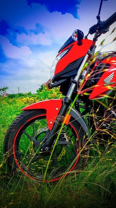 Red Honda Motorcycle in Lush Green Field Under Blue Sky