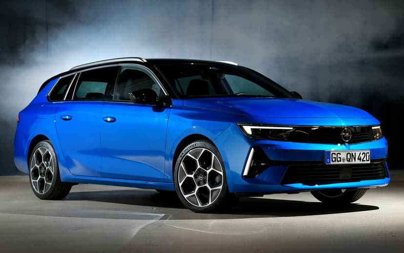 Blue station wagon with black roof and geometric wheels parked in a dark studio with white background smoke.