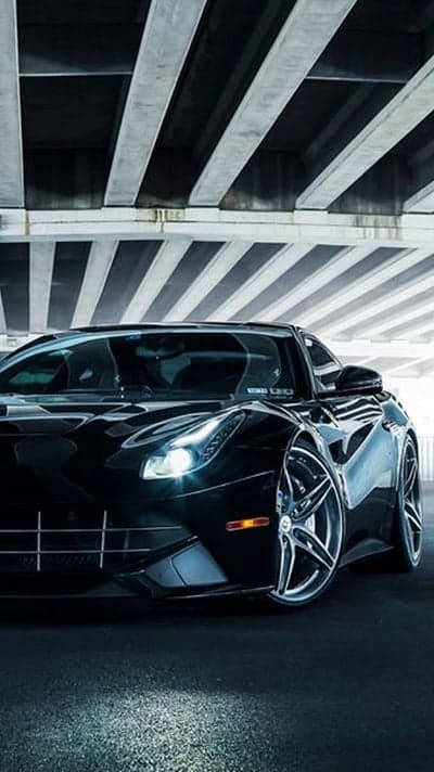 Sleek black Ferrari under a concrete overpass