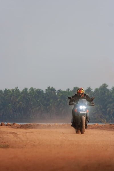 Motorcyclist riding on a sandy beach with palm trees