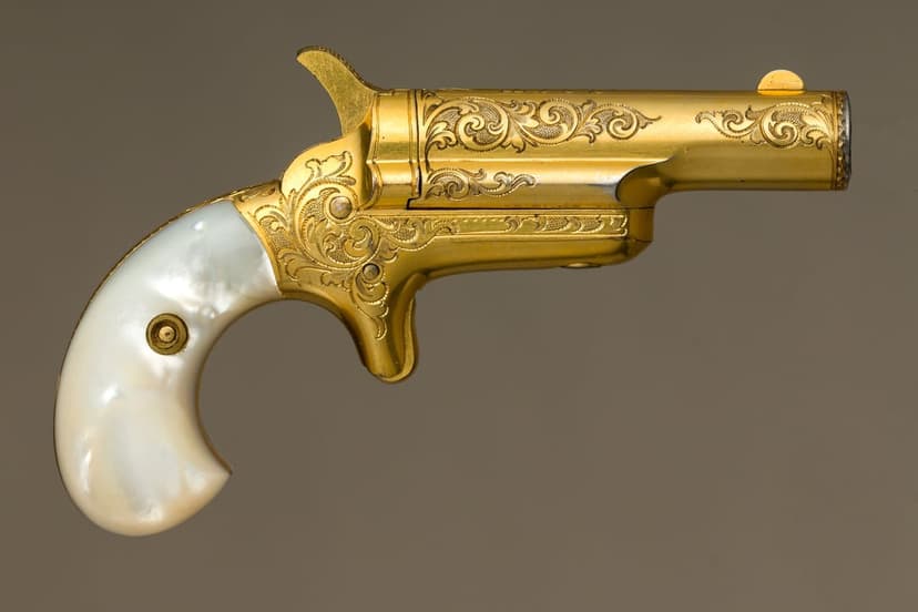 Gold-plated derringer pistol featuring intricate scrollwork engravings and a polished mother-of-pearl handle.