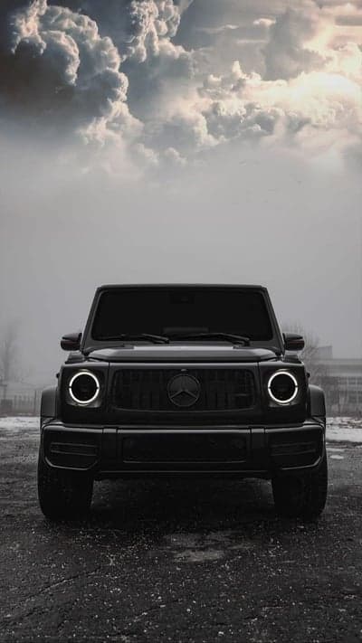 Black Mercedes-Benz G-Wagon parked under dramatic clouds
