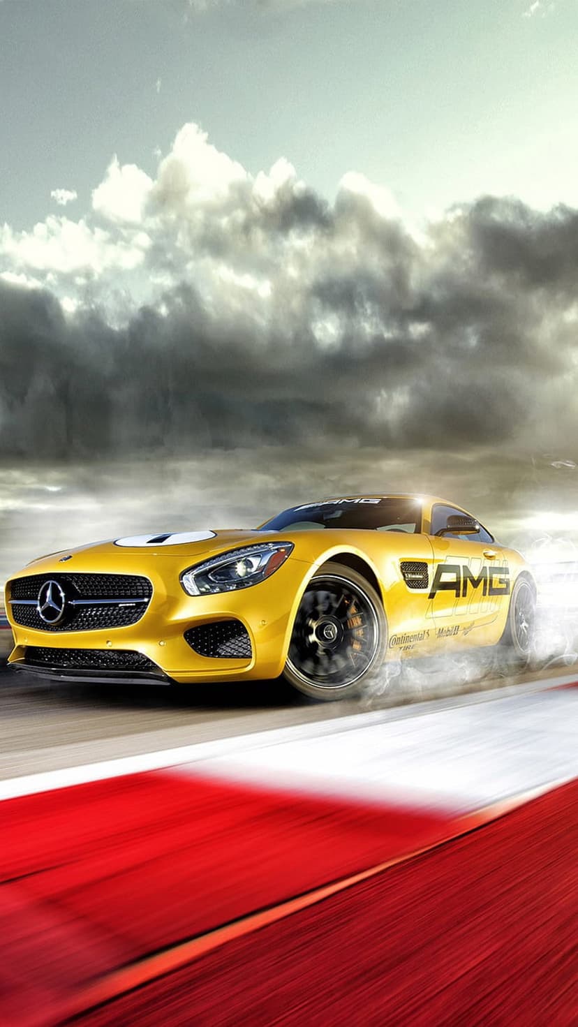 Yellow Mercedes-AMG GT S sports car drifting on a race track with clouds of white tire smoke and a stormy sky.