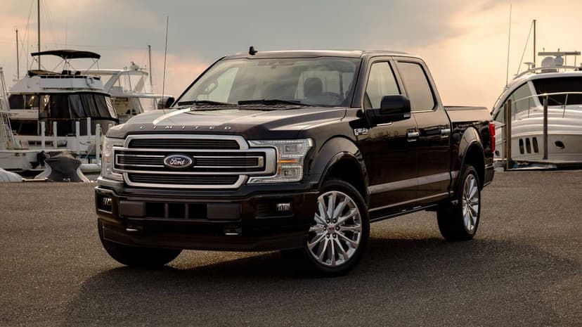 Black Ford F-150 Limited truck parked at a marina with yachts under a golden sunset sky.