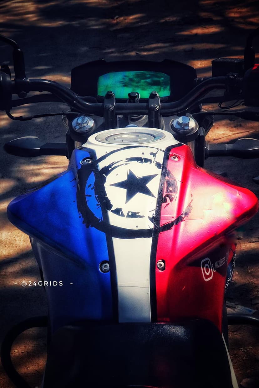 Captain America shield emblem painted on a curved motorcycle fuel tank with red white and blue metallic details.