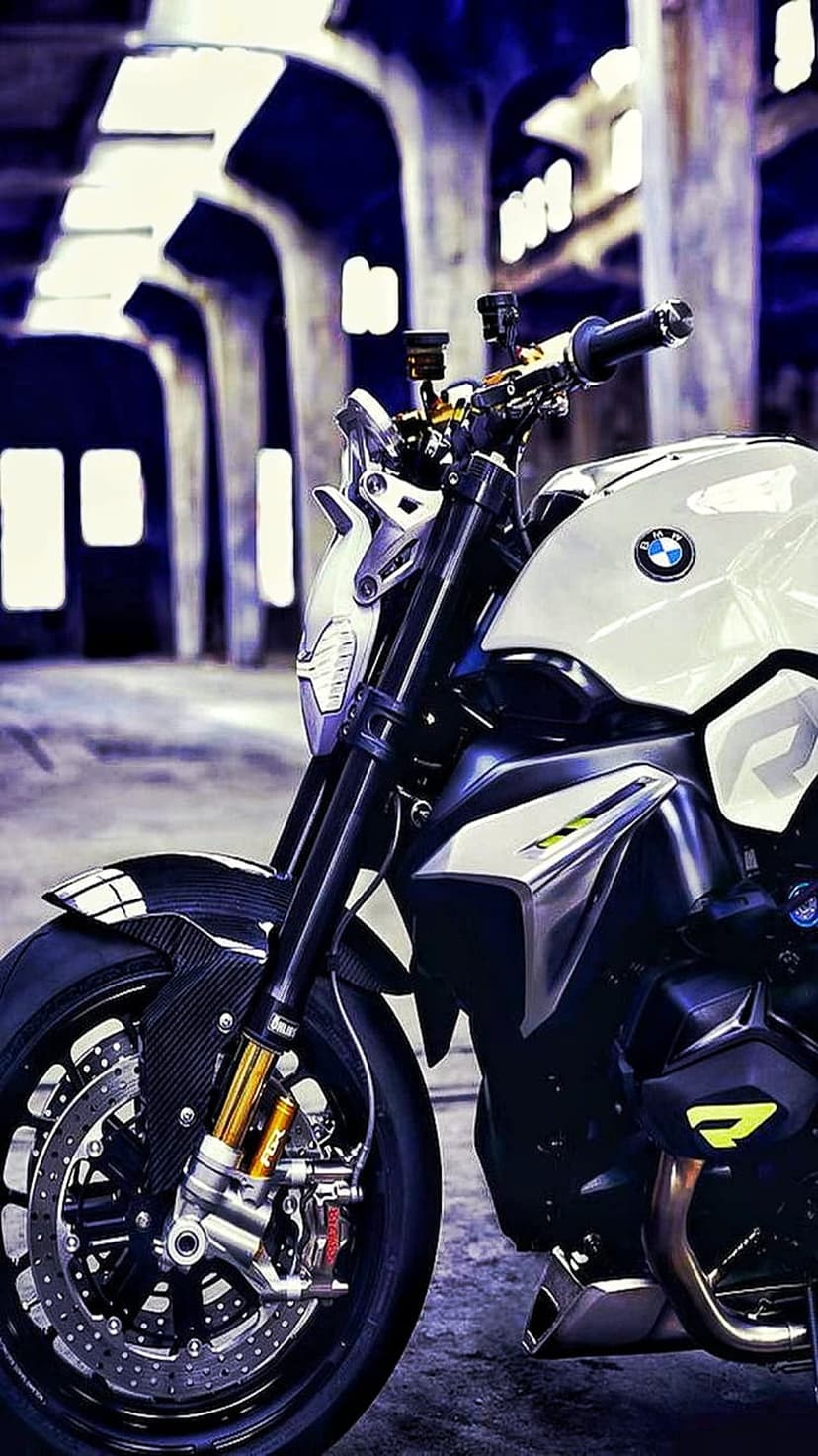BMW motorcycle front headlight and golden forks with black fairings in a dimly lit industrial setting.