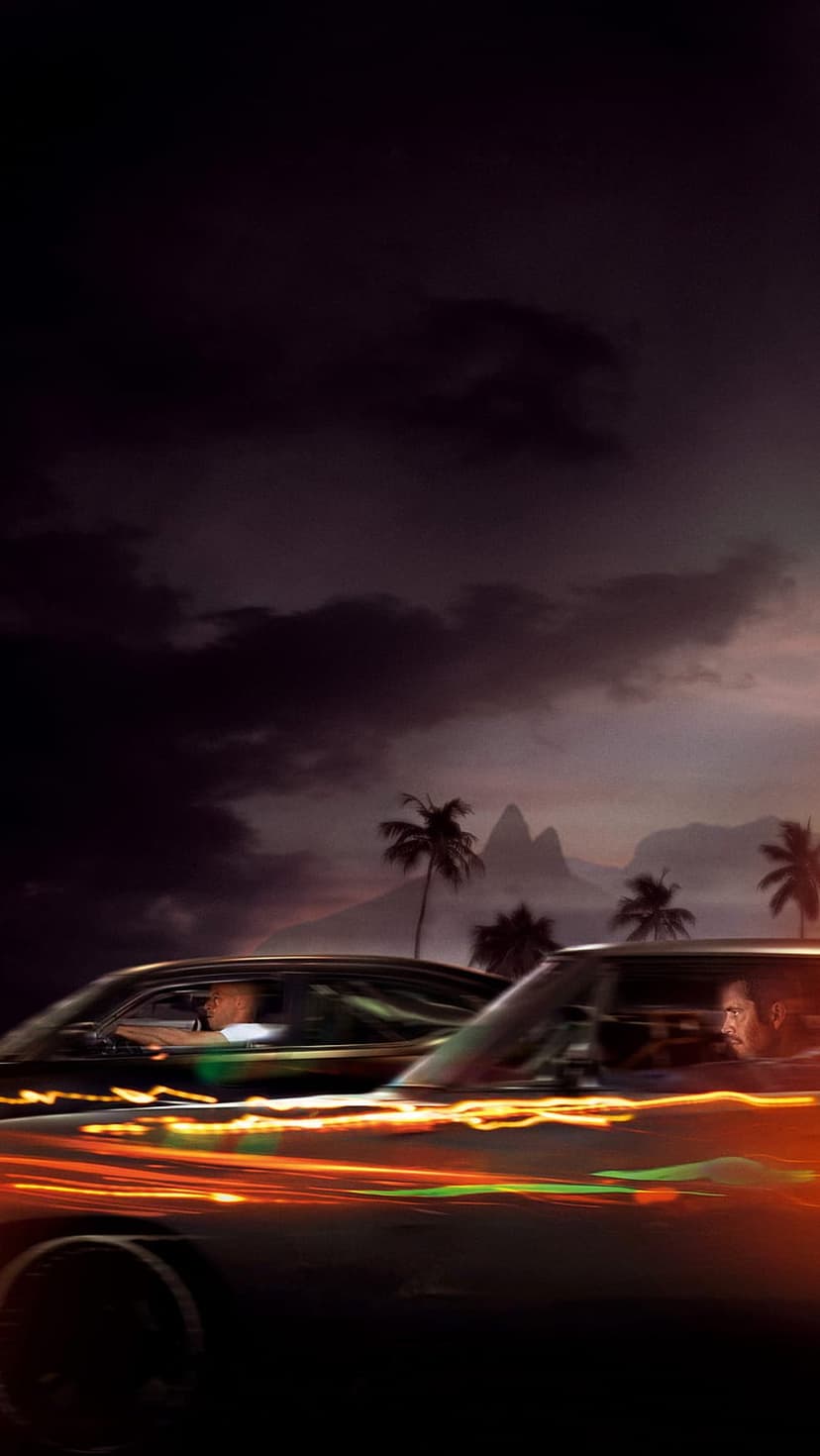 Two muscle cars race down a tropical road at dusk with palm trees and mountains under a cloudy sunset sky.