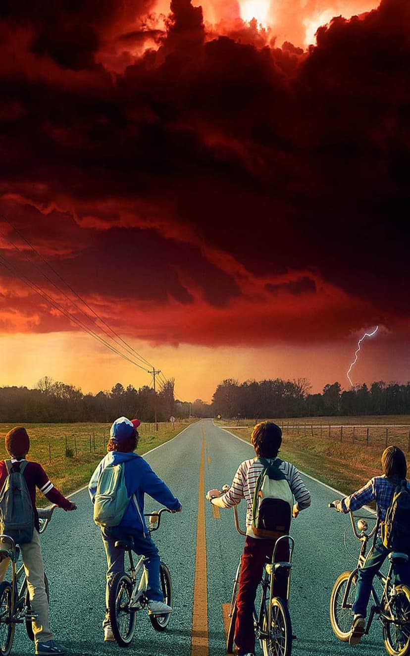 Four children on bicycles stand on a paved road facing a dark red sky with a distant lightning strike.