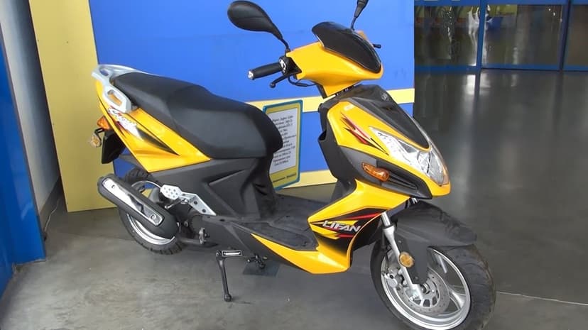 Vibrant yellow Lifan motor scooter with black accents parked on a grey floor against a blue and yellow wall.