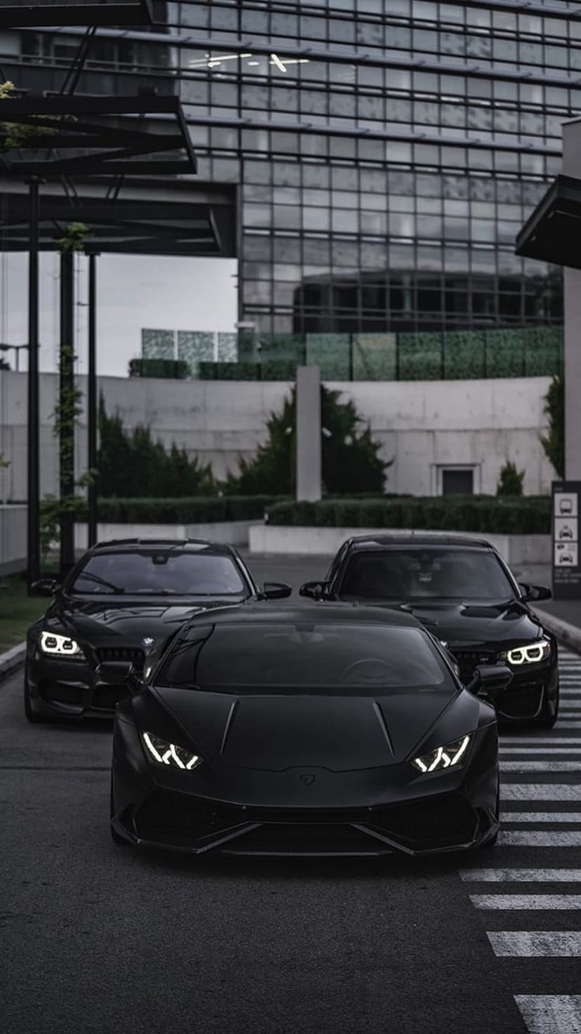 Three black luxury vehicles parked near a modern glass building create a dark aesthetic for phone screens.