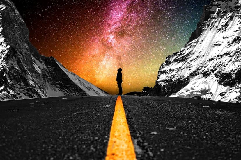 A traveler stands on a dark highway gazing at a vibrant purple nebula between monochromatic snowy mountains.
