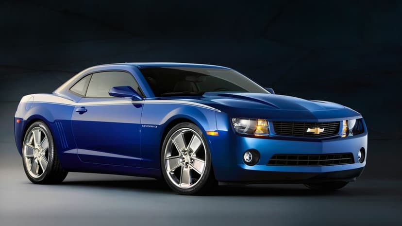 Metallic blue Chevrolet Camaro with silver wheels and white racing stripe against a dark textured background.