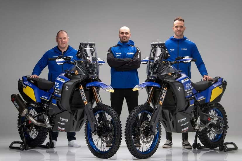 Two blue Yamaha Ténéré rally motorcycles and three team members in a professional grey studio setting.
