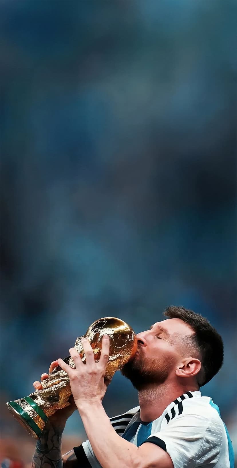 Lionel Messi kisses the gold FIFA World Cup trophy while wearing a blue and white striped Argentina jersey.
