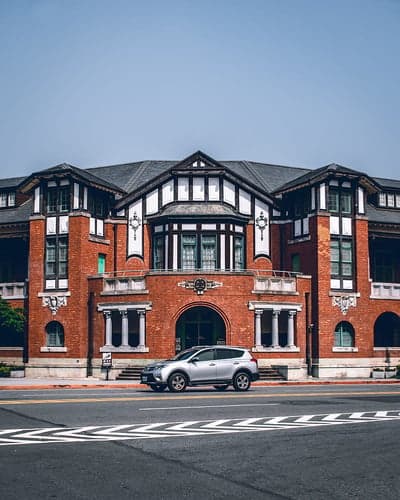 Vintage Red Brick Building with Silver SUV