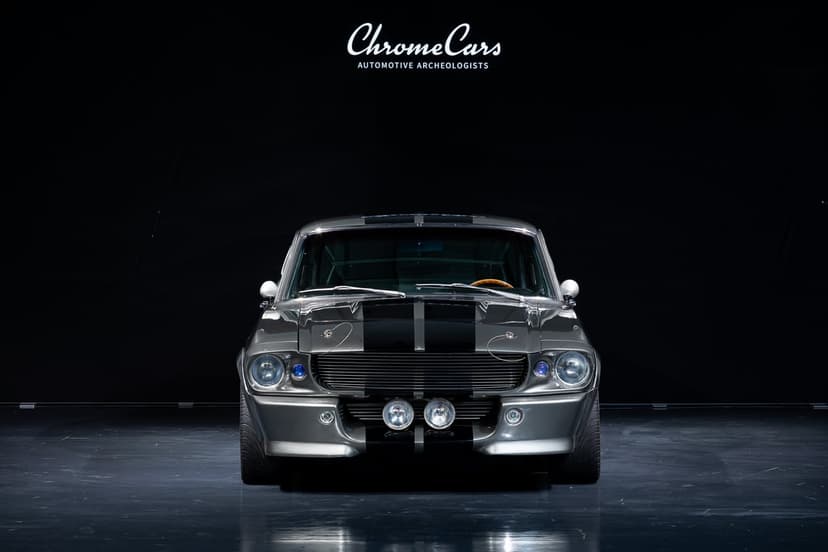 Front view of a grey Shelby GT500 Eleanor Mustang with black stripes against a dark studio background.