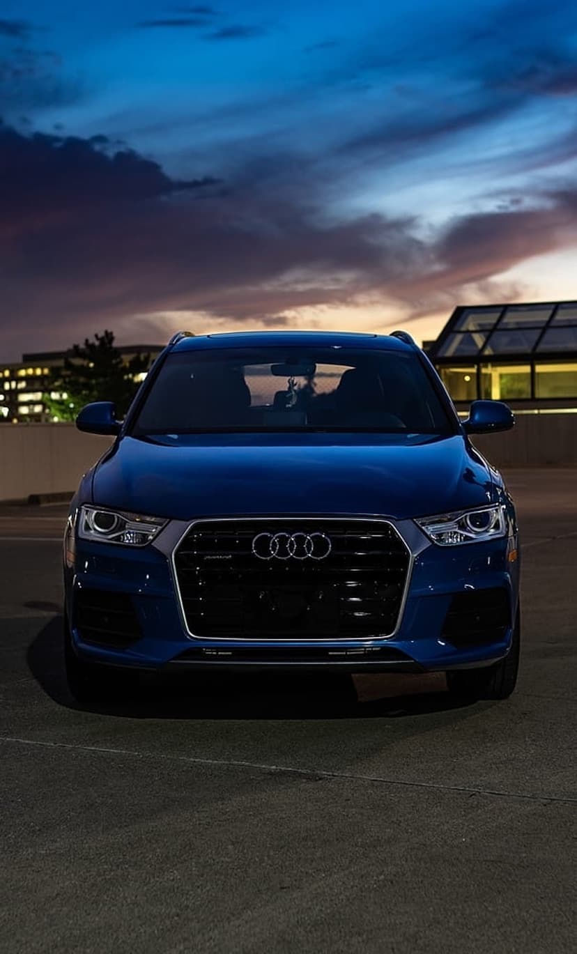 Blue Audi SUV parked on an urban rooftop lot under a purple and orange twilight sky with glowing headlights.