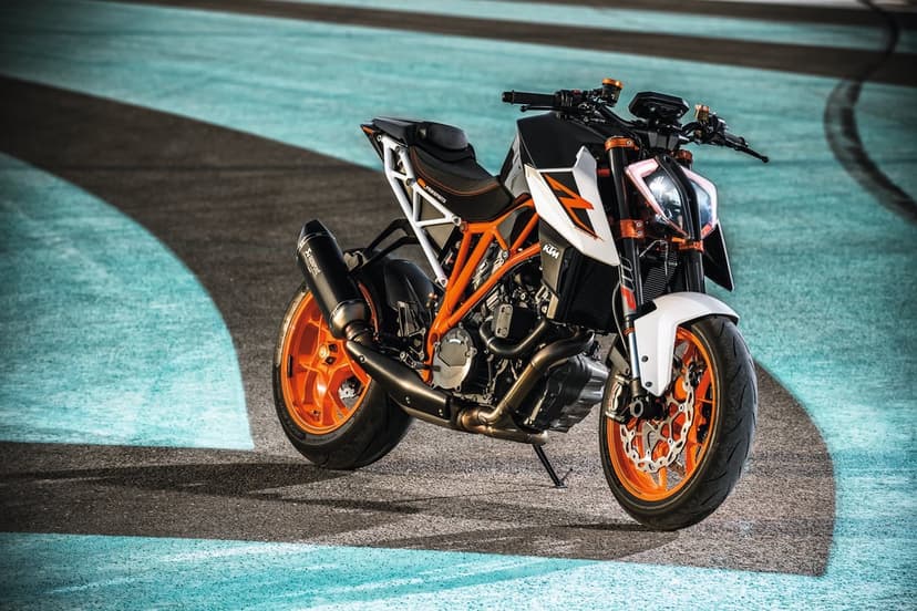 KTM 1290 Super Duke R motorcycle with orange frame and rims parked on a cyan and grey paved racetrack.