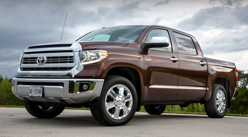 Brown Toyota Tundra pickup truck with chrome accents parked on an asphalt road under a cloudy sky.