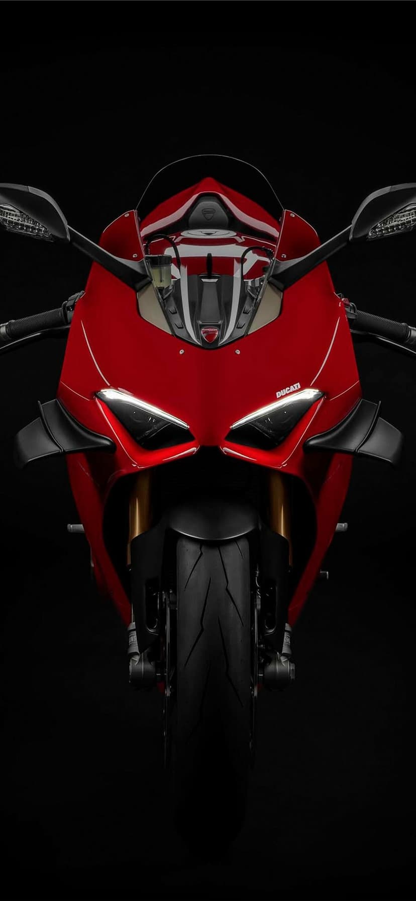 Front view of a red Ducati Panigale motorcycle with glowing LED headlights and aerodynamic winglets.