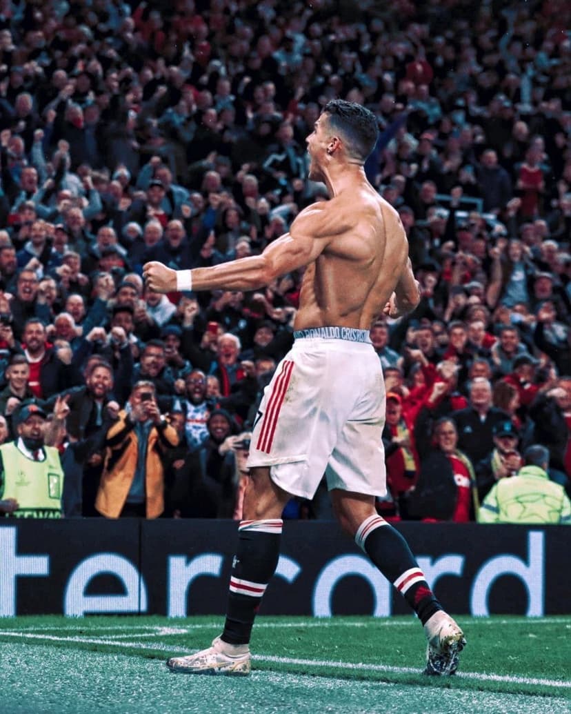 Cristiano Ronaldo shirtless from behind, showing muscular back and white shorts in a crowded stadium celebration.