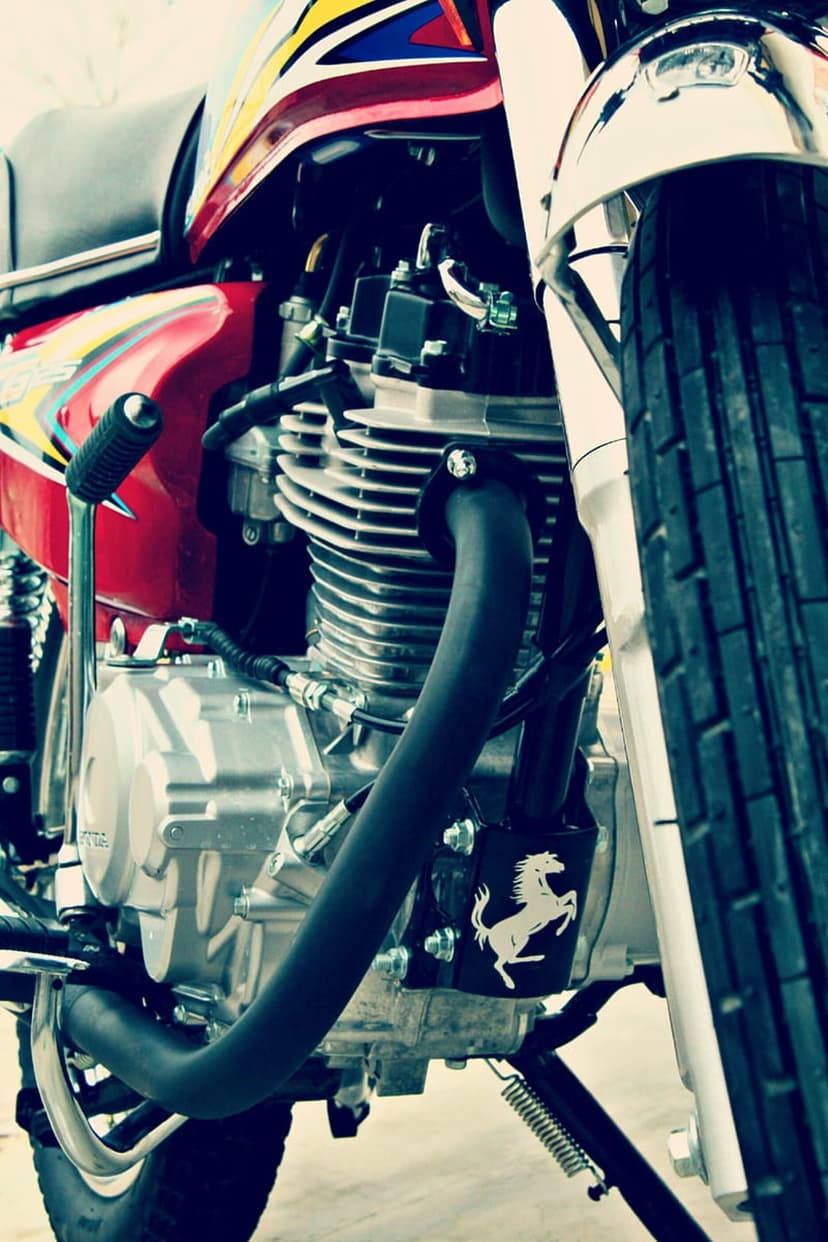 Motorcycle engine details featuring a silver block, black exhaust, and a white prancing horse on a black emblem.