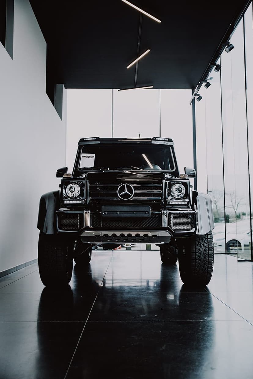 Black Mercedes-Benz G-Wagon SUV with a chrome star emblem parked on a polished floor inside a modern showroom.