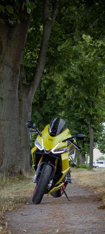 Vibrant Aprilia Sportbike in Woodland Phone Background