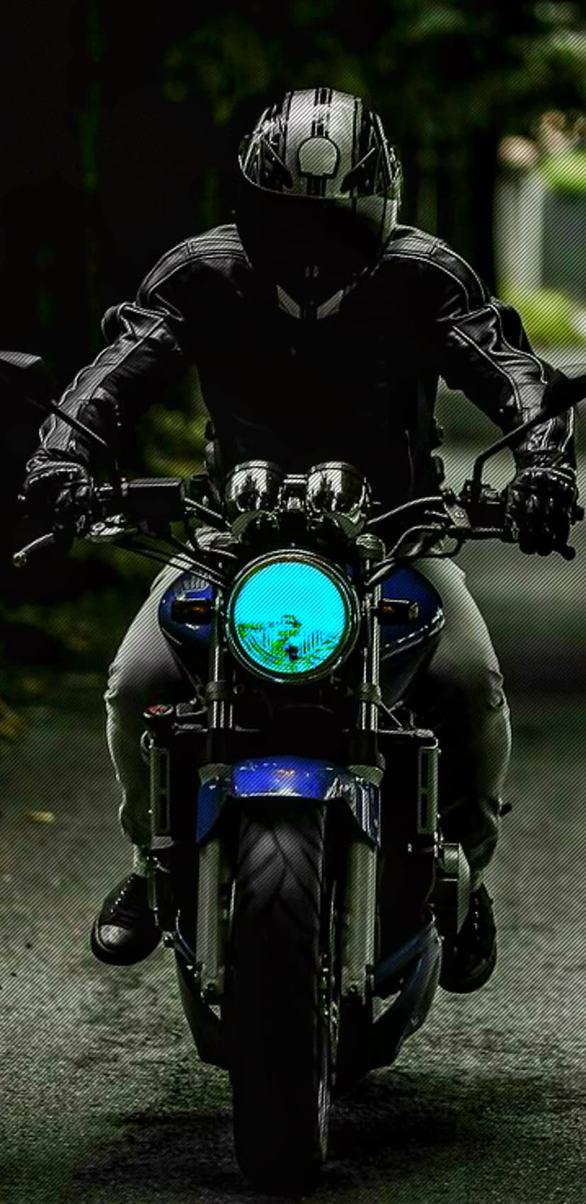 Motorcyclist in black leather rides a blue bike with a glowing headlight on a dark highway at high speed.