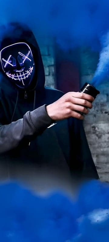 Person in Purge Mask Holds Blue Smoke Bomb