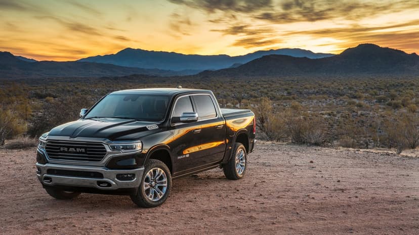 Black Ram 1500 pickup truck in a desert landscape with mountains and a golden sunset sky background.
