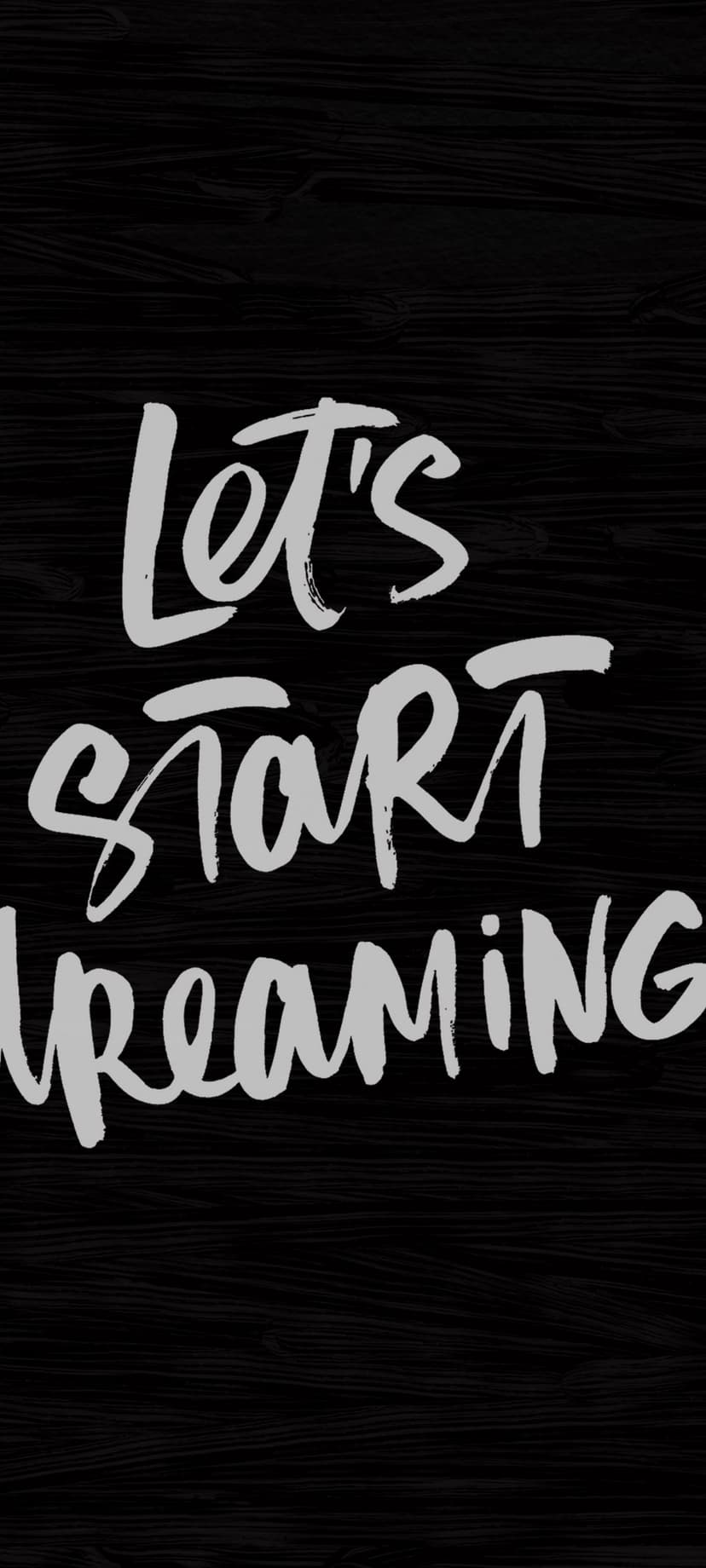 White brush script phrase Let's Start Dreaming centered on a dark, gritty textured charcoal background.